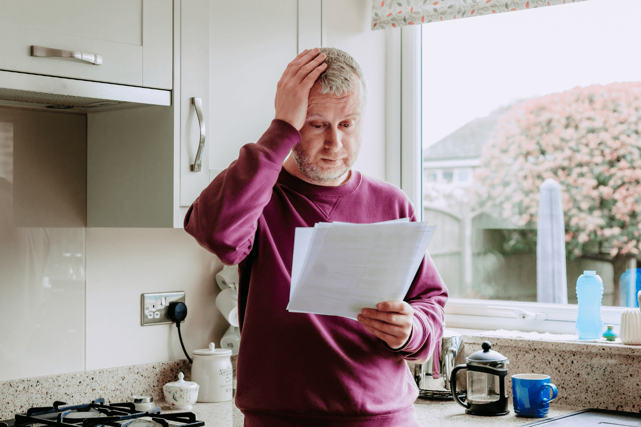 Man holding power bill with one hand on his head in despair.